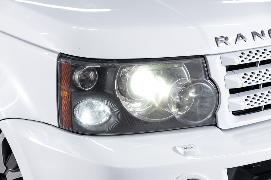 Headlight and grill of a white Land Rover, brought into C's Autohaus