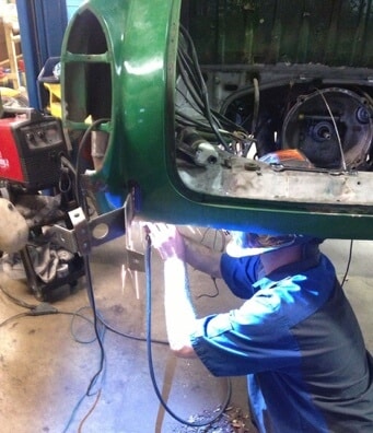 auto repair in Centerville, Oh image of C's mechanic underneath raised green volkswagen welding under tire frame
