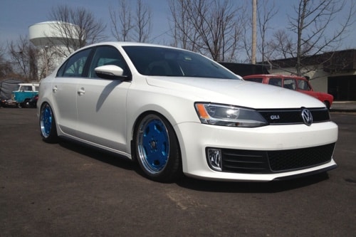 C's Autohaus - Volkswagen Scheduled Maintenance Explained in Centerville Oh, image of white Volkswagen GLI with blue rims parked outside of shop