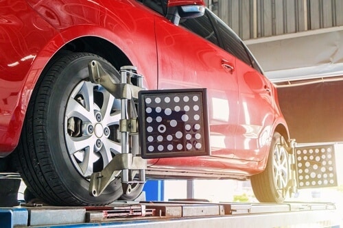5 Tell-Tale Signs You Need A Wheel Alignment with C's Autohaus in Centerville, OH; image of red mini cooper on alignment machine in shop bay area