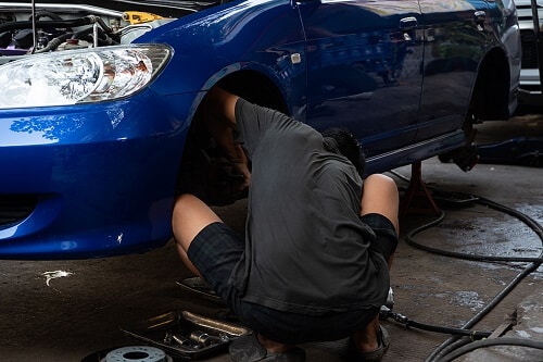 Brake Repair & Brake Inspection in Centerville, OH | C’s Autohaus. Image of a mechanic checking brakes of car in an auto repair shop.