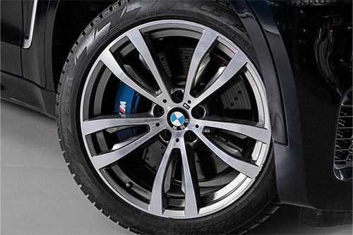 Tire Repair & Services | C's Autohaus in Centerville, OH. Close-up image of a black BMW's aluminum alloy wheel and new tires.