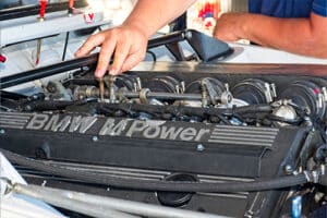 Are BMW Cars Hard to Maintain? How to Make It Easier? | C’s Autohaus in Centerville, OH. Image of a BMW mechanic checking a BMW engine. Concept image of BMW maintenance and repairs.