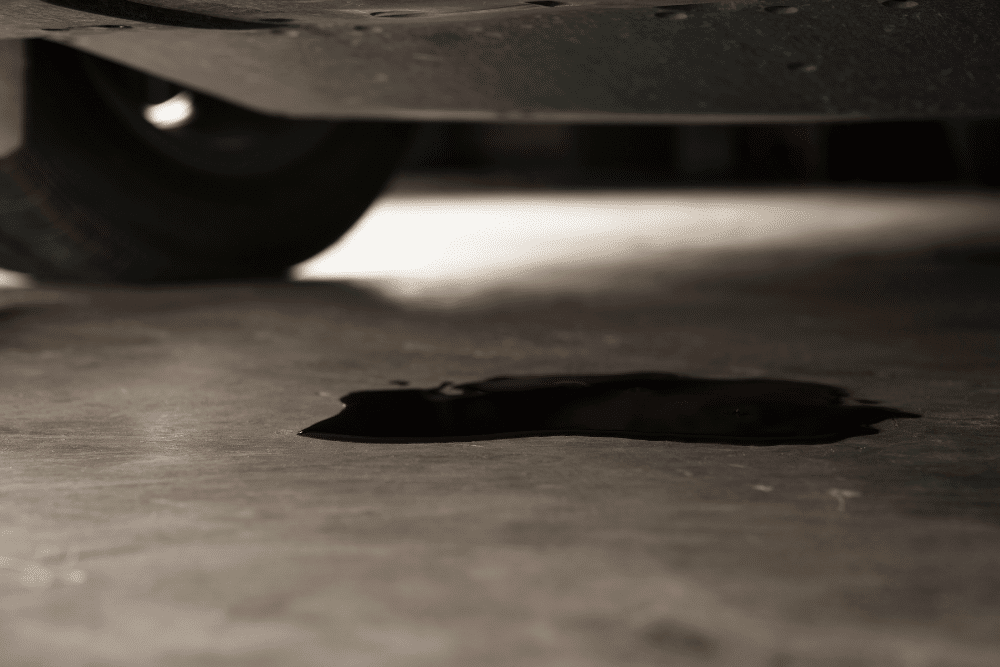 BMW 3 Series oil leak repair in Centerville, OH by C's Autohaus. Image of a dark oil puddle beneath a vehicle, stressing the importance of professional service to protect engine performance and vehicle safety.