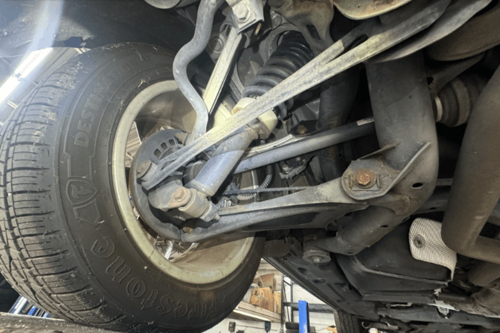 Suspension repair after pothole damage, auto repair in Centerville, OH by C’s Autohaus. Image of a vehicle’s front suspension components, including control arms, shock absorbers, and steering linkage, highlighting professional suspension diagnostics and safe, stable vehicle handling.